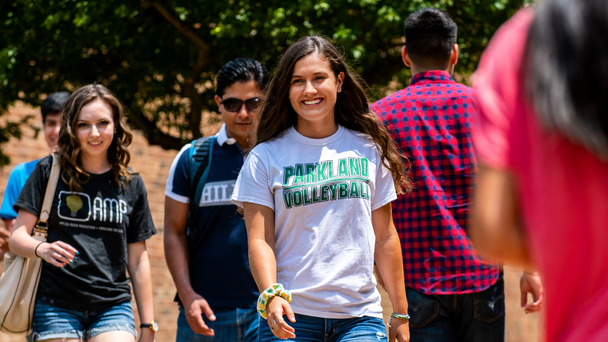 Smiling female student walking among crowd on campus